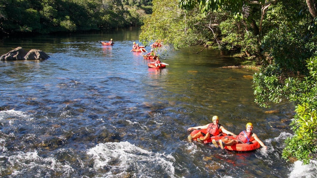 People enjoying river tubing through a scenic forested area.