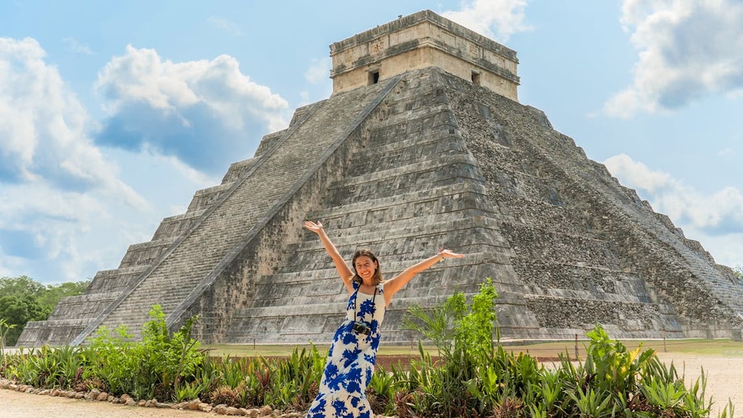 Woman posing in front of Chichen Itza pyramid during her tour in Mexico.
