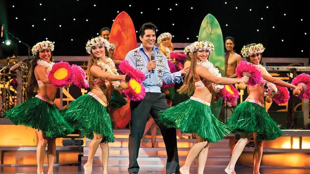 Dancers performing hula at Rock-A-Hula Show with surfboards in the background.