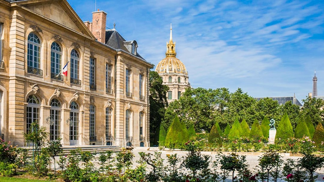 Rodin Museum garden with sculptures and view of Les Invalides dome in Paris.