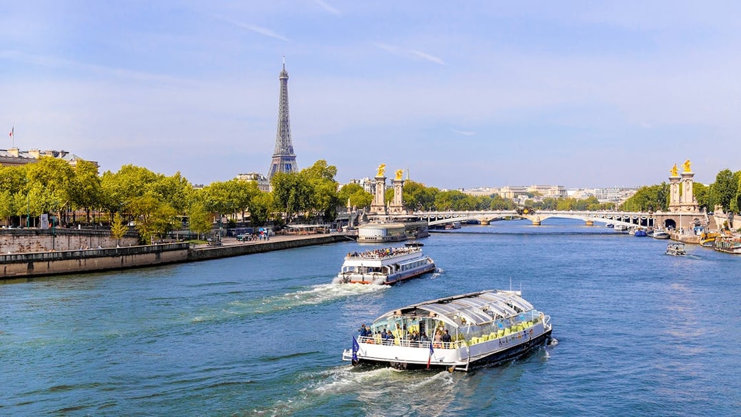 Seine River cruise boats with Eiffel Tower and Pont Alexandre III in Paris.