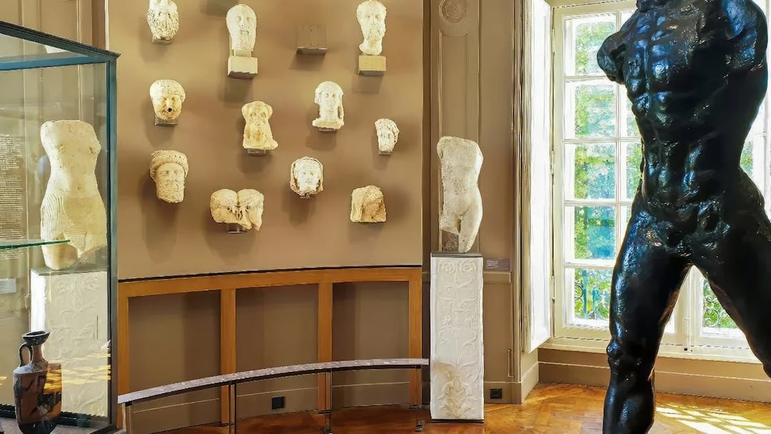 Rodin Museum gallery with sculptures and busts displayed on walls and pedestals.