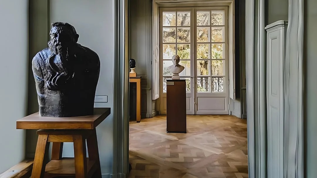 Rodin Museum interior with sculptures and large window view.