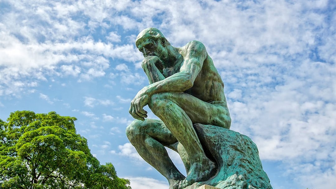 Rodin's The Thinker statue against a blue sky at The Muse.
