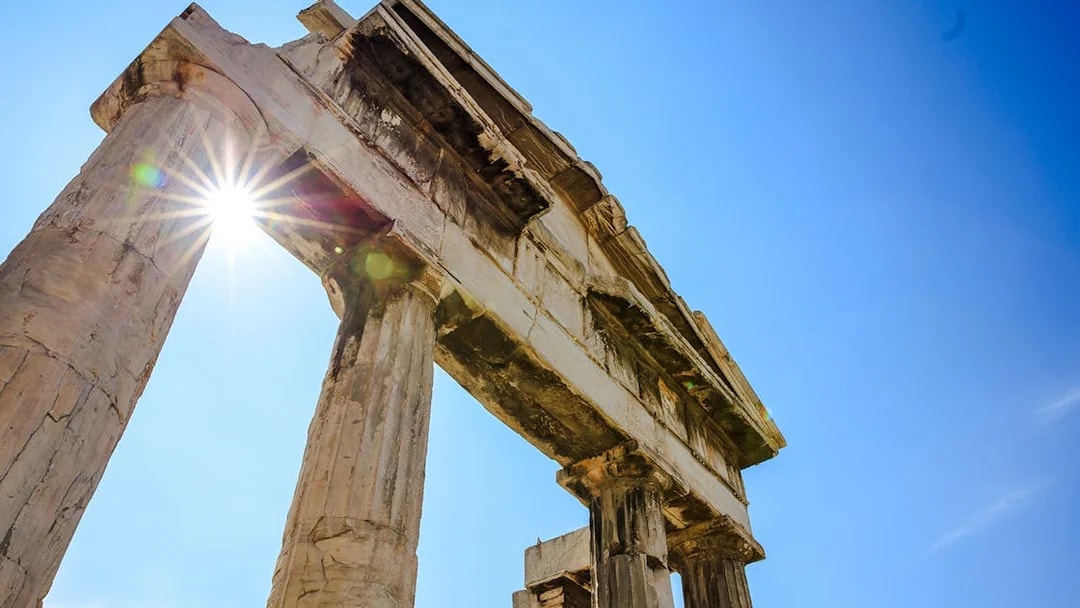 Ancient columns of the Roman Agora in Athens, Greece, with sunlight peeking through.