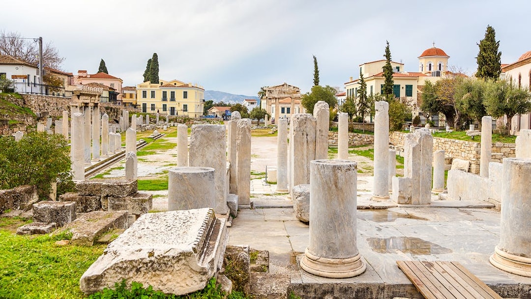 Roman Agora ruins with columns in Athens, Greece, surrounded by historic buildings.