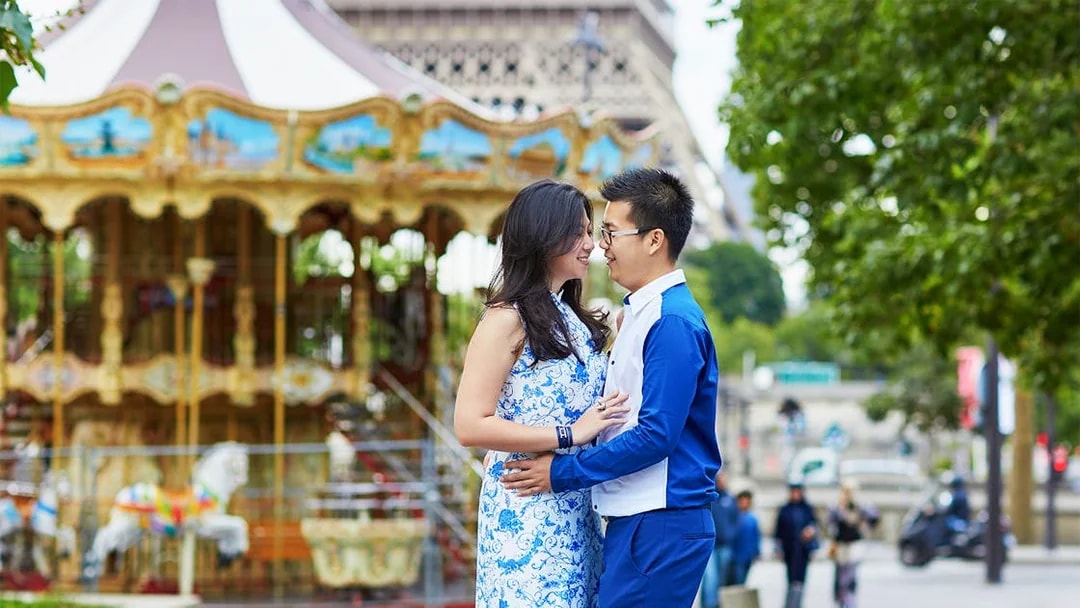 Couple embracing near carousel with Eiffel Tower in background, Paris.