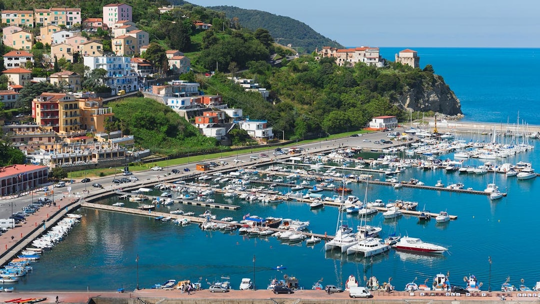 Amalfi Coast marina with colorful hillside buildings and boats docked in the harbor.