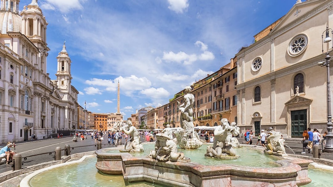 Tourists walking by the Fountain of Neptune in Piazza Navona, Rome.