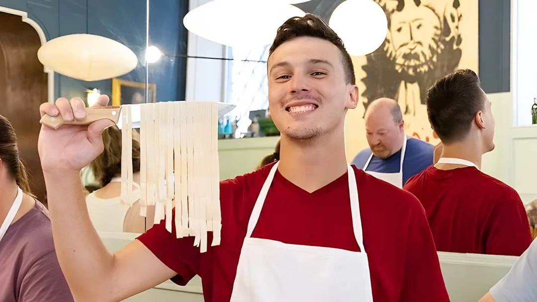 Cooking class participant holding fresh fettuccine in Rome near Piazza Navona.