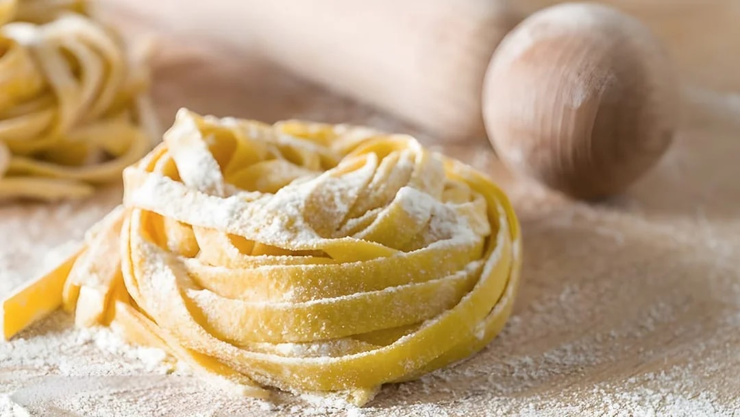 Fettuccine dough with flour and rolling pin in Rome cooking class.