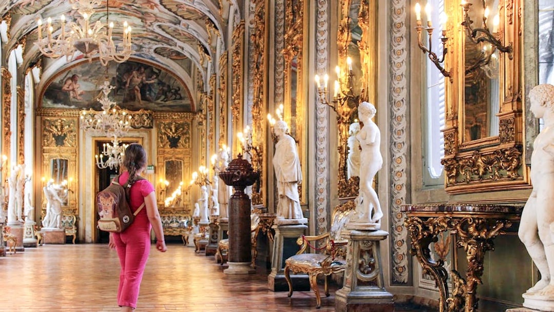 Girl exploring ornate hall with statues at Doria Pamphilj Gallery, Rome.