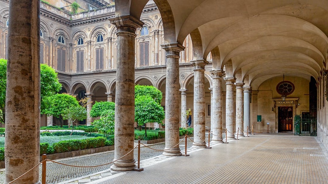 Doria Pamphilj Courtyard with stone columns and lush greenery in Rome.