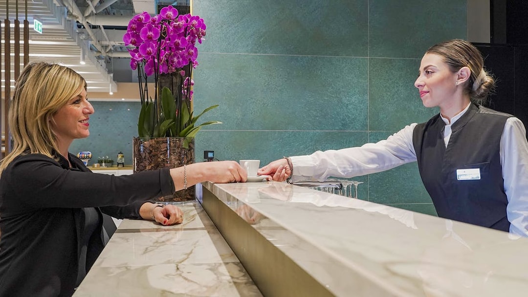 Customer receiving a drink at Rome Fiumicino Airport premium lounge counter.