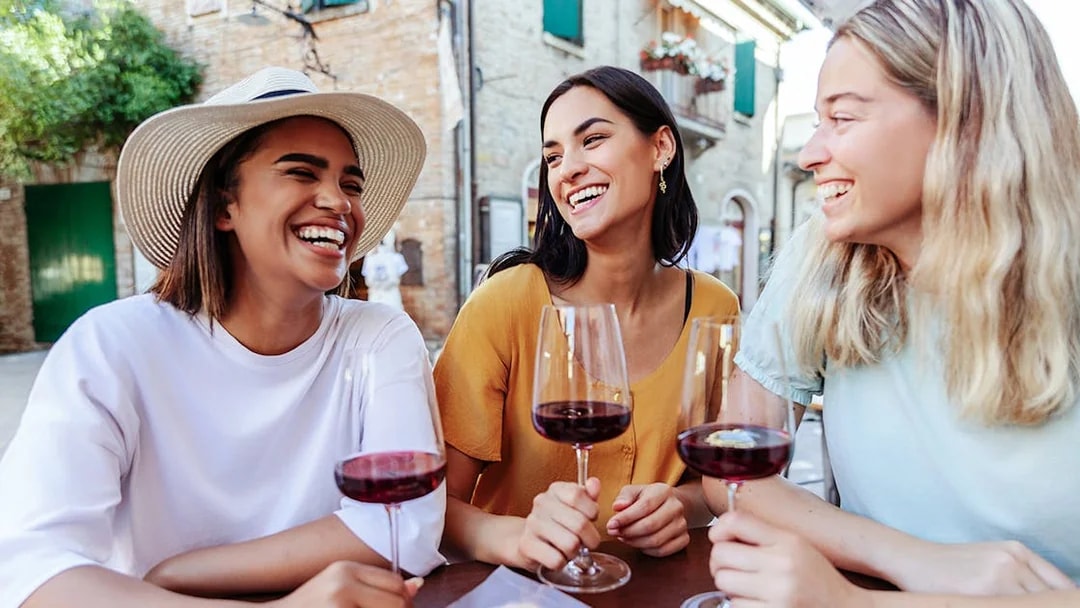 Friends enjoying wine at an outdoor café in a European village.