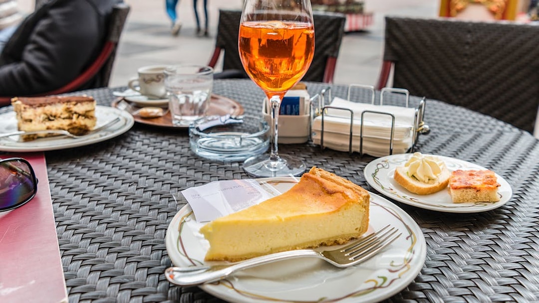 Slice of tiramisu and cheesecake on a cafe table in an outdoor setting.