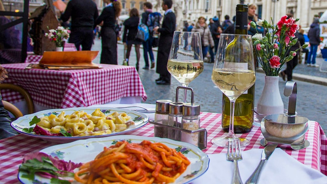 Pasta dishes and wine on a checkered table in Trastevere, Rome.