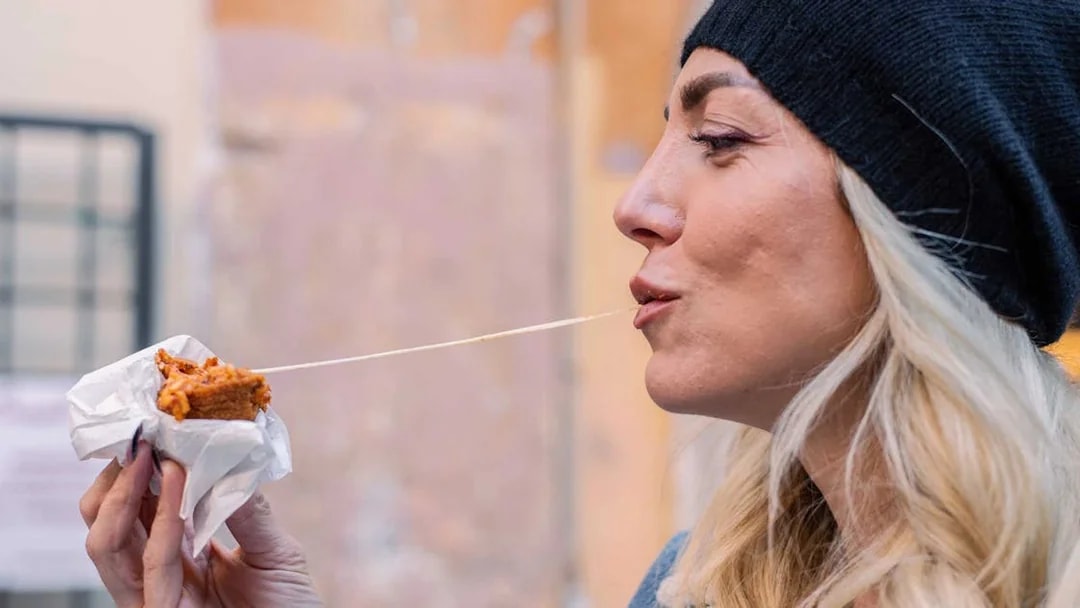 Woman enjoying a cheesy snack outdoors.