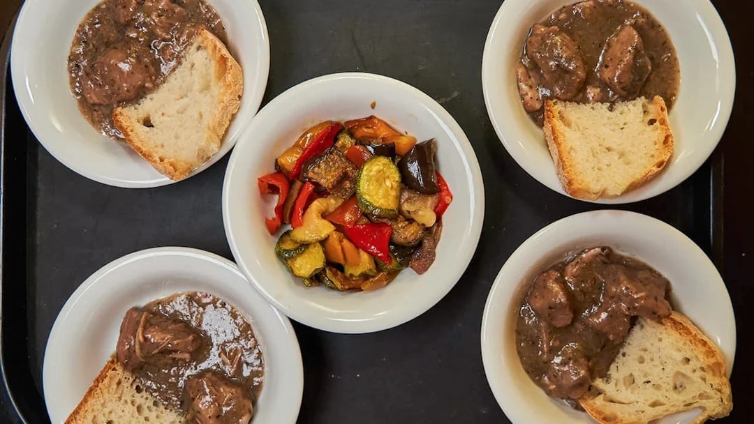 Bowls of Italian stew with bread and roasted vegetables on a Trastevere food tour.