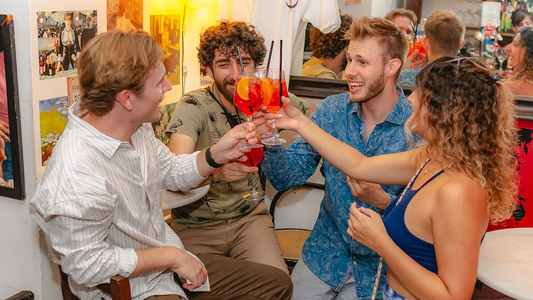 Group of friends toasting with drinks in a Rome bar.