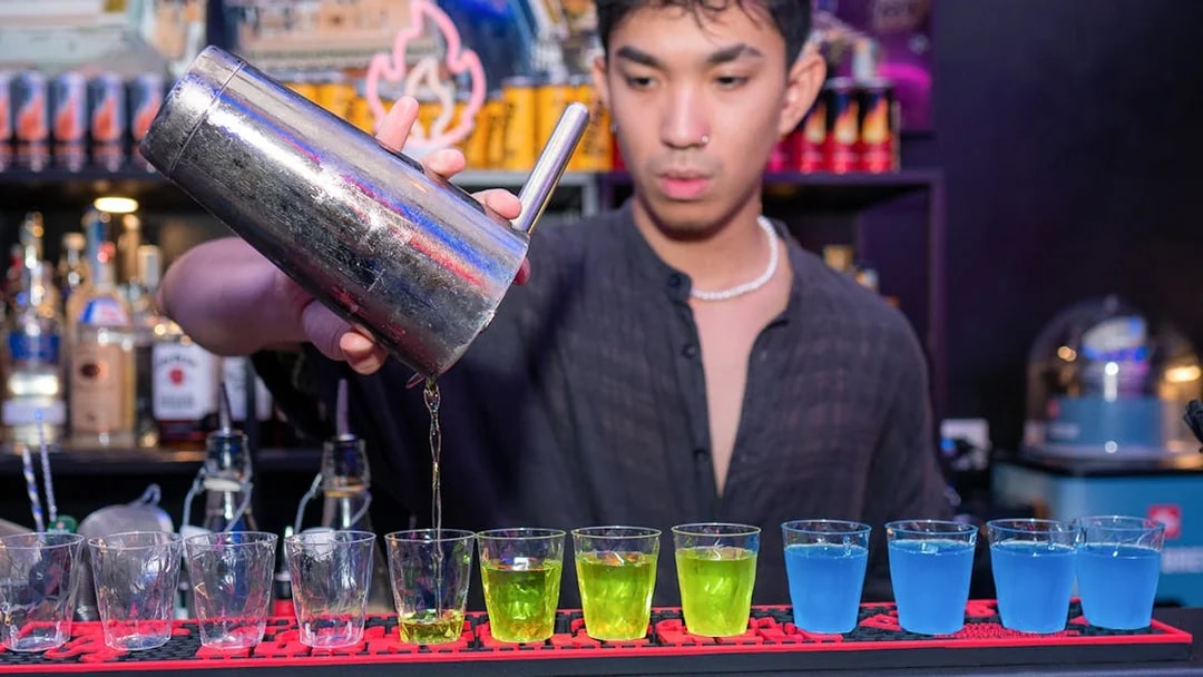 Bartender pouring colorful shots at a bar in Rome.