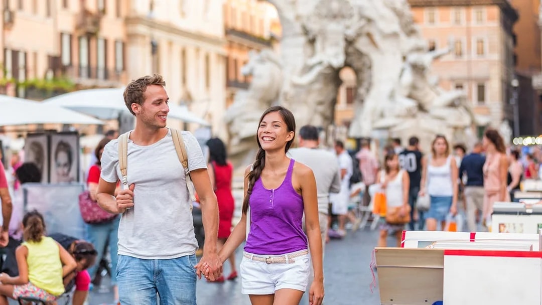 Couple walking near the Fountain of the Four Rivers in Rome.