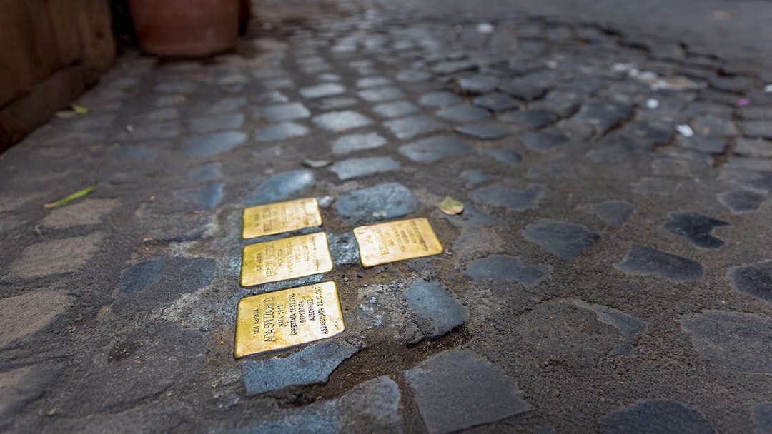 Stumbling stones embedded in cobblestone street in Rome.