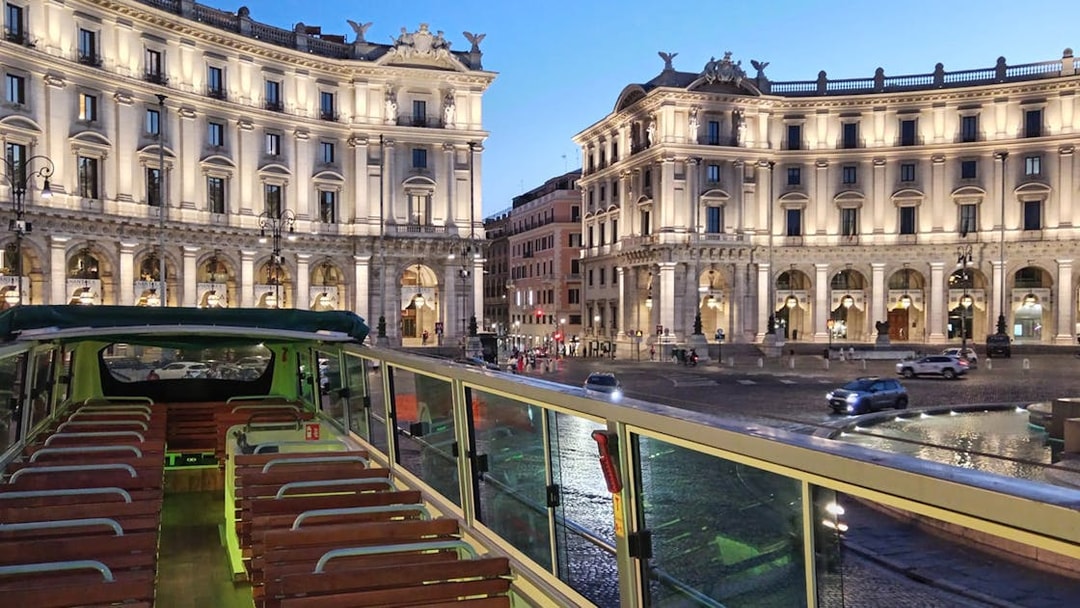 Open-top vintage bus in Rome's Piazza della Repubblica at dusk.