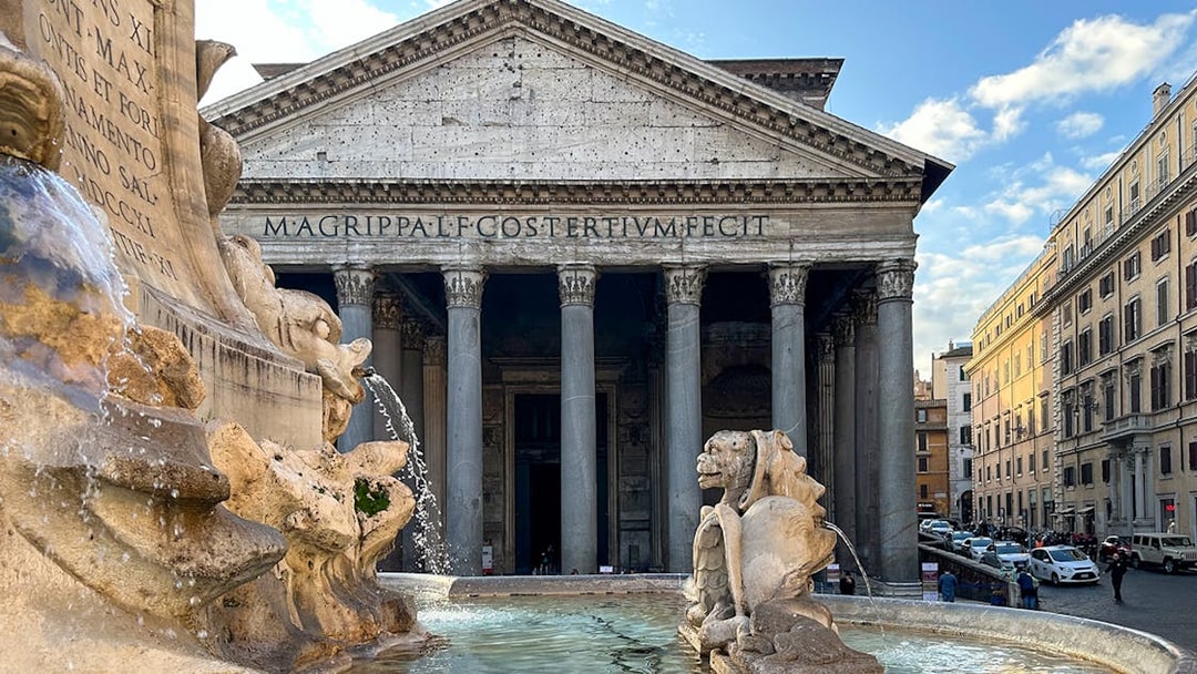 Pantheon facade in Rome with fountain in foreground.
