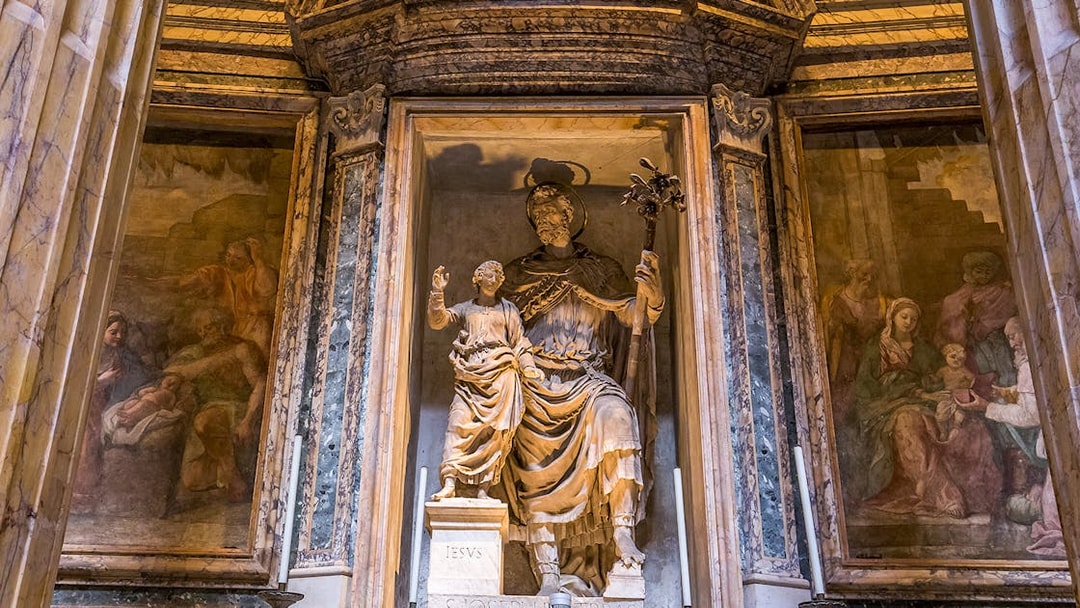 Statue inside the Roman Pantheon depicting a religious figure with a child, surrounded by frescoes.