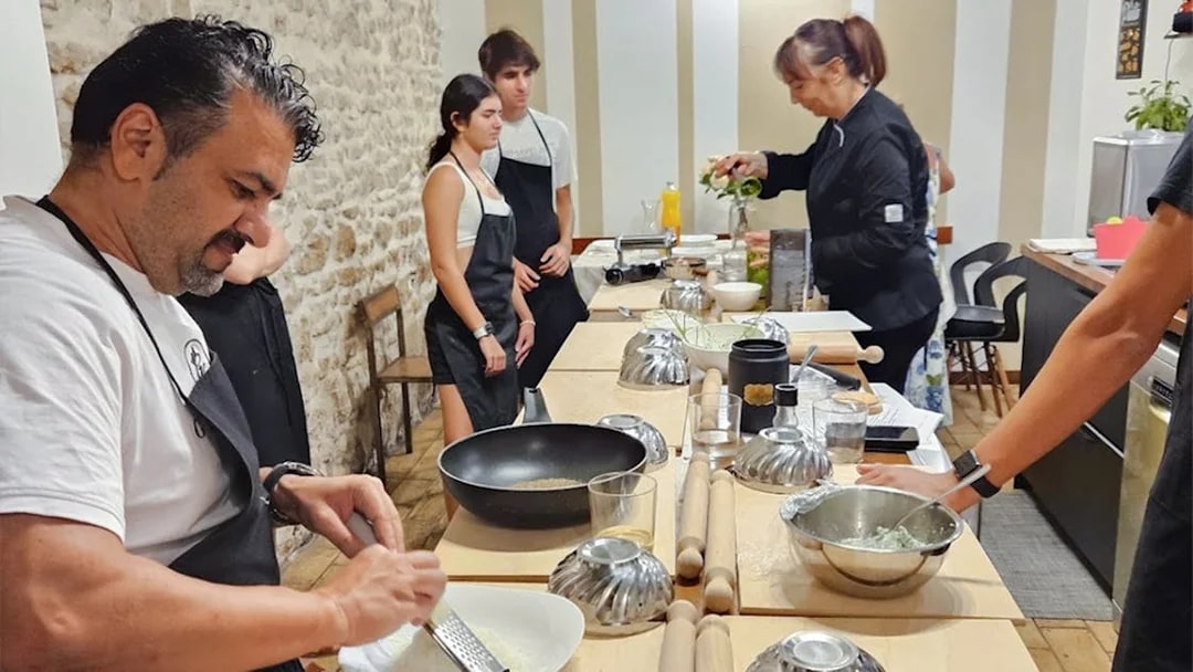 Participants in a Rome cooking class preparing dishes at a kitchen counter.