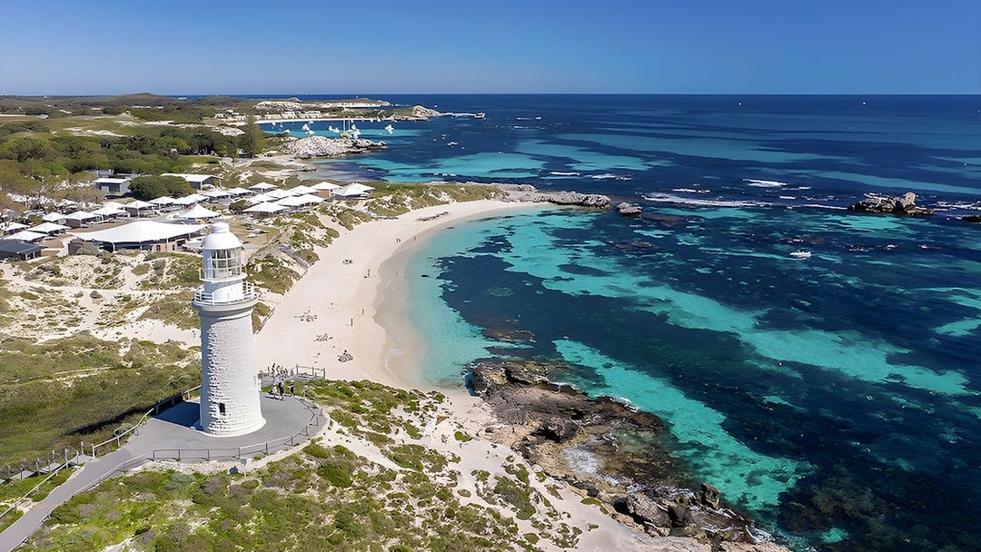 Rottnest Island coastline with lighthouse and turquoise waters, view from above.