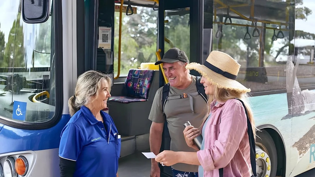 Tourists boarding a bus, assisted by a staff member, with luggage in the background.
