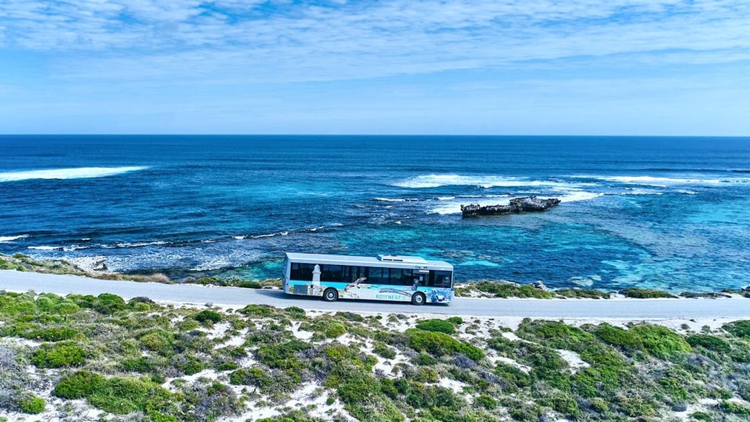 Bus on coastal road with ocean view, Rottnest Island tour, Western Australia.