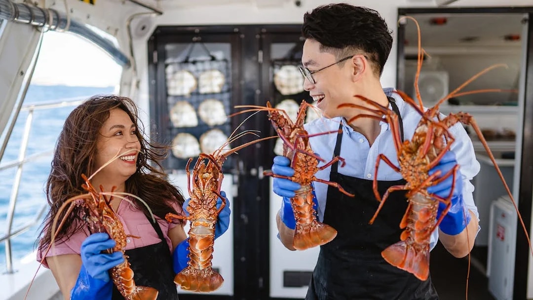 Guests holding lobsters on Rottnest Island Luxe Seafood Cruise.