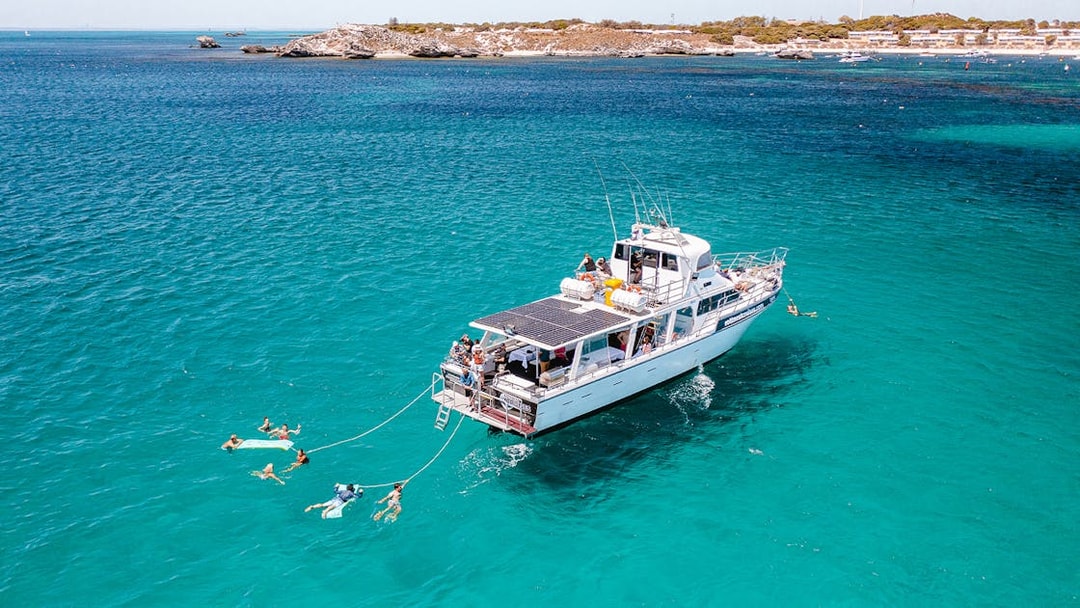 Luxury boat with swimmers in turquoise waters near Rottnest Island.