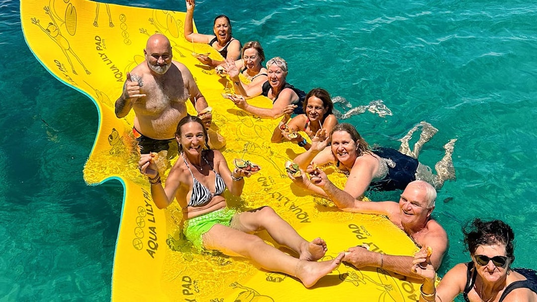 Group enjoying seafood on a floating mat during Rottnest Island Luxe Seafood Cruise.