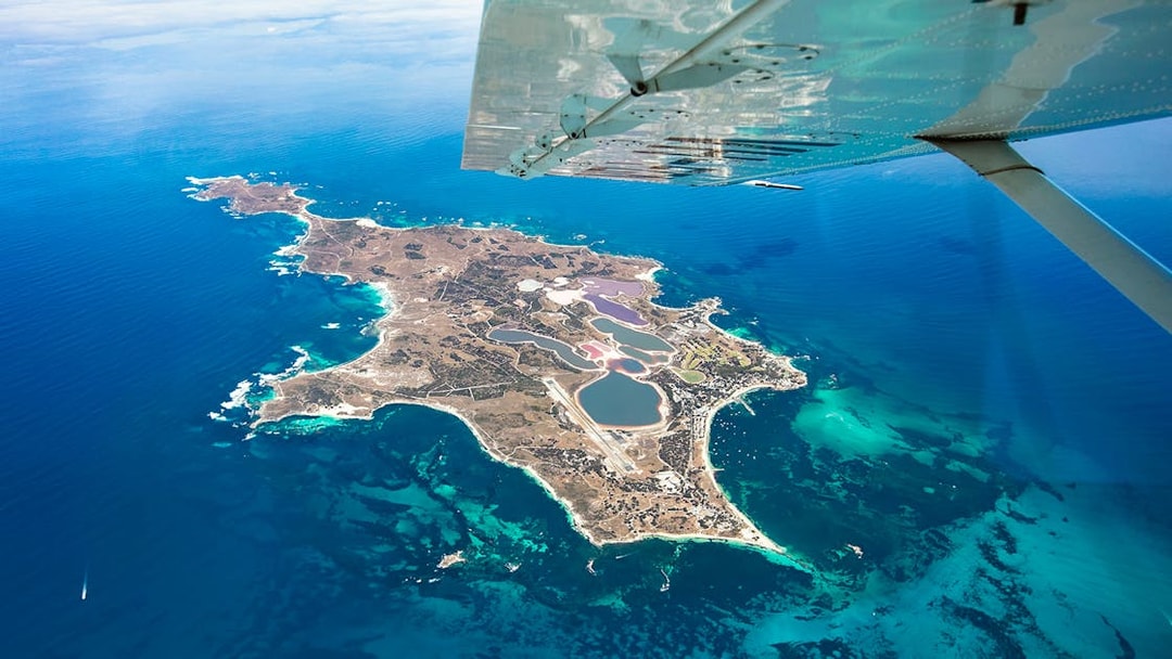 Aerial view of Rottnest Island from a plane, showcasing coastline and clear waters.