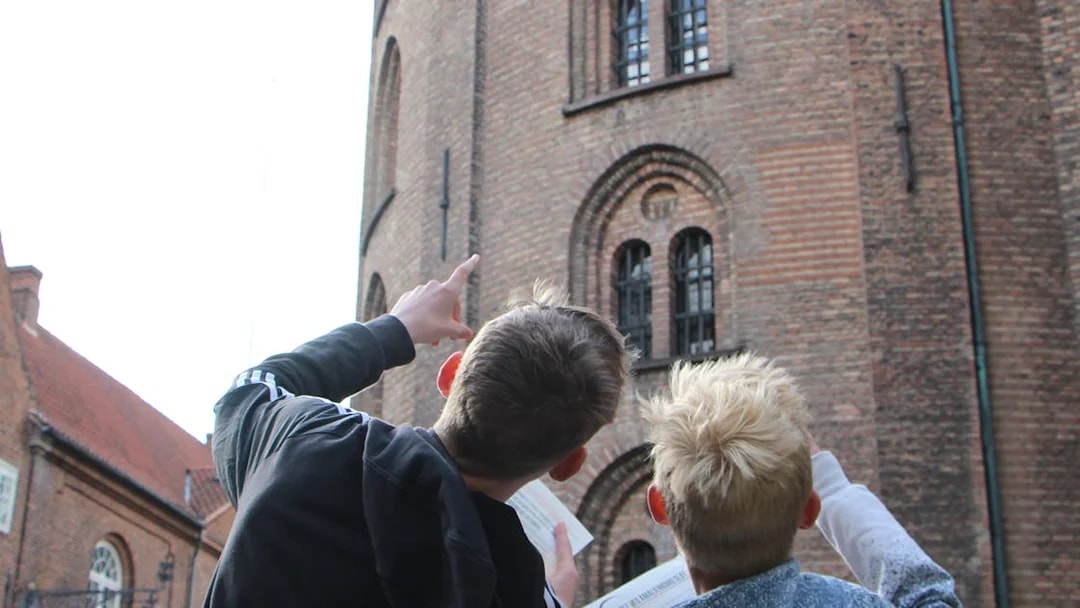 Visitors pointing at Round Tower in Copenhagen during a murder mystery experience.