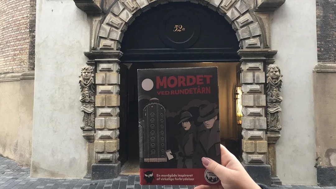 Murder Mystery Experience brochure held in front of Round Tower entrance, Copenhagen.