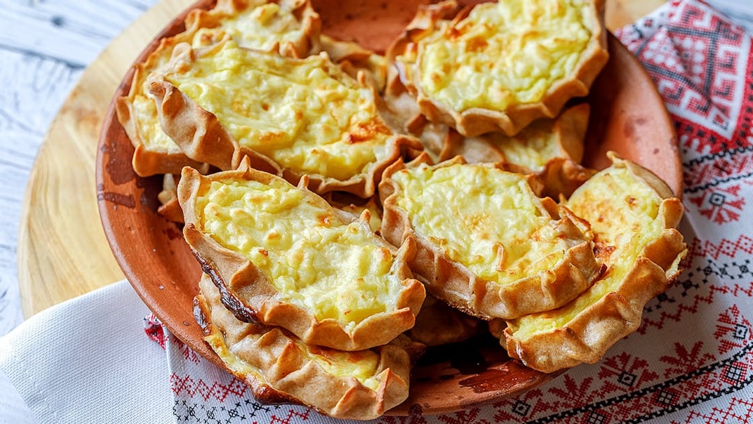 Traditional Finnish Karelian pies on a wooden plate, served on a patterned cloth.