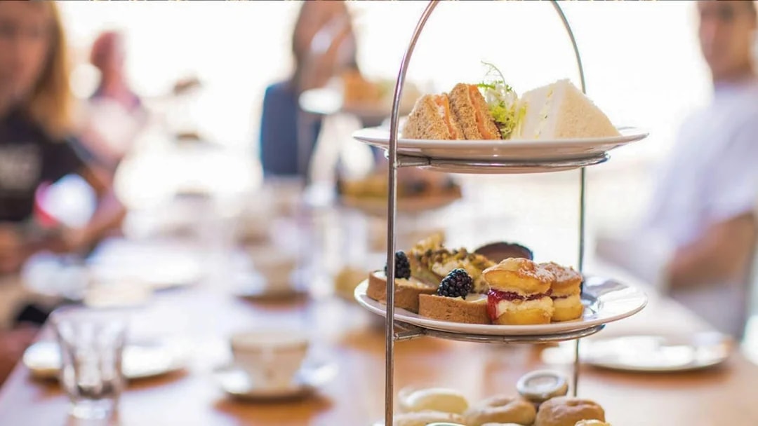 Afternoon tea with scones, sandwiches, and pastries on a tiered stand at Westminster Abbey.