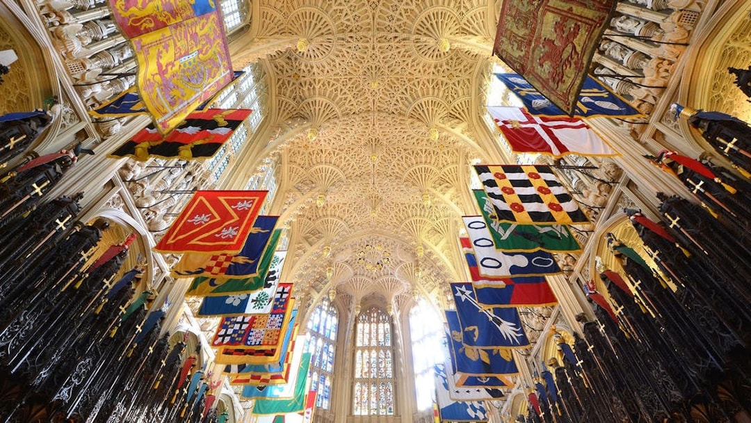 Westminster Abbey interior with colorful banners and ornate ceiling, Royal London Tour.