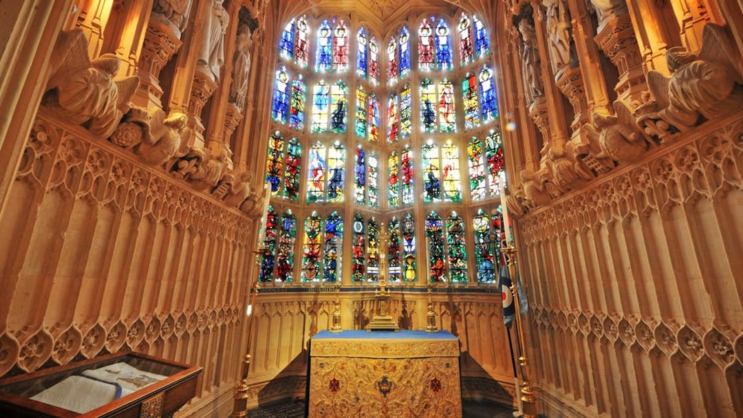 Stained glass windows and ornate altar inside Westminster Abbey, London.