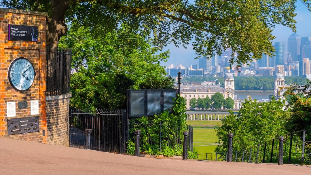 Royal Observatory Greenwich entrance with view of London skyline and historic buildings.