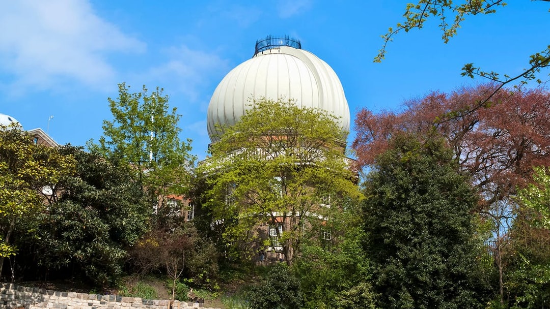 Equatorial telescope dome at Griffith Observatory, surrounded by trees, Los Angeles, USA.