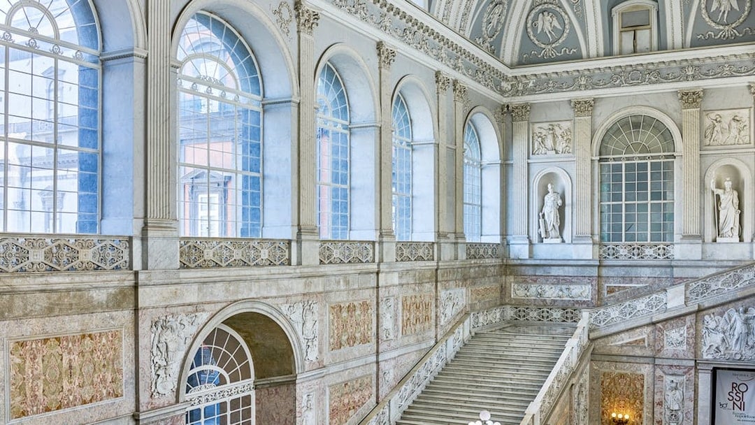 Grand staircase and ornate windows inside the Royal Palace of Naples.