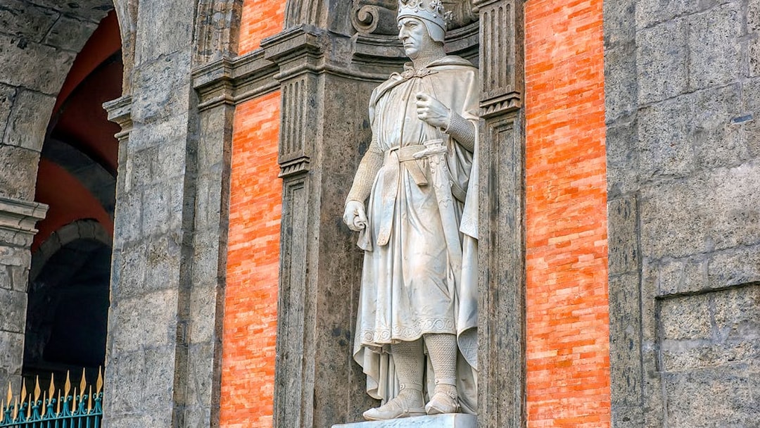 Statue of a crowned figure in the Royal Palace of Naples gardens.