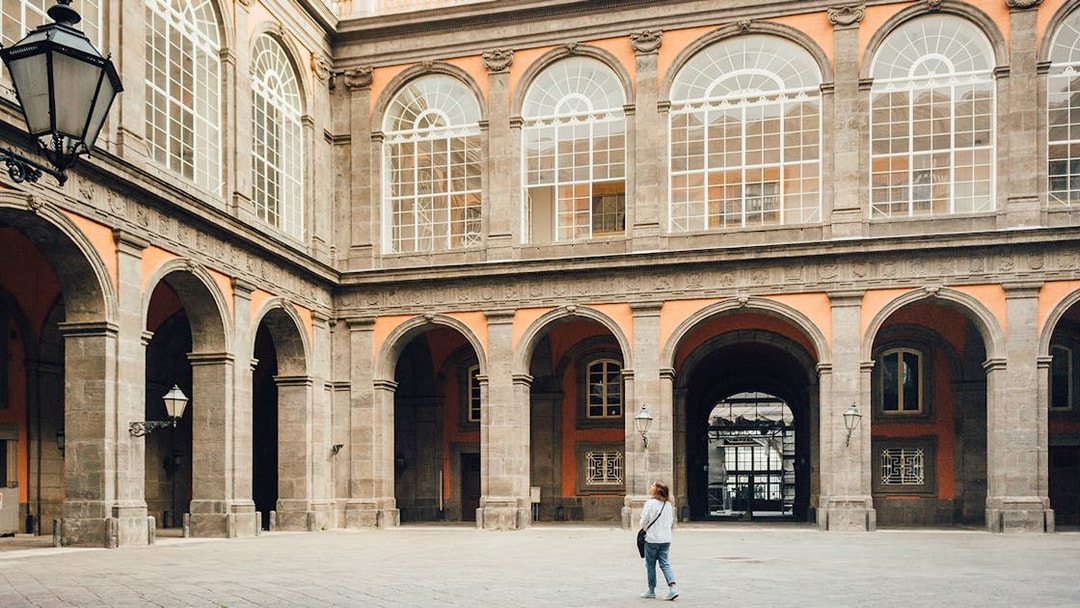 Woman walking in the courtyard of the Royal Palace of Naples, Italy.