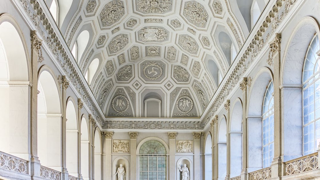 Ceiling and sculptures inside the Royal Palace of Naples, featuring ornate architectural details.